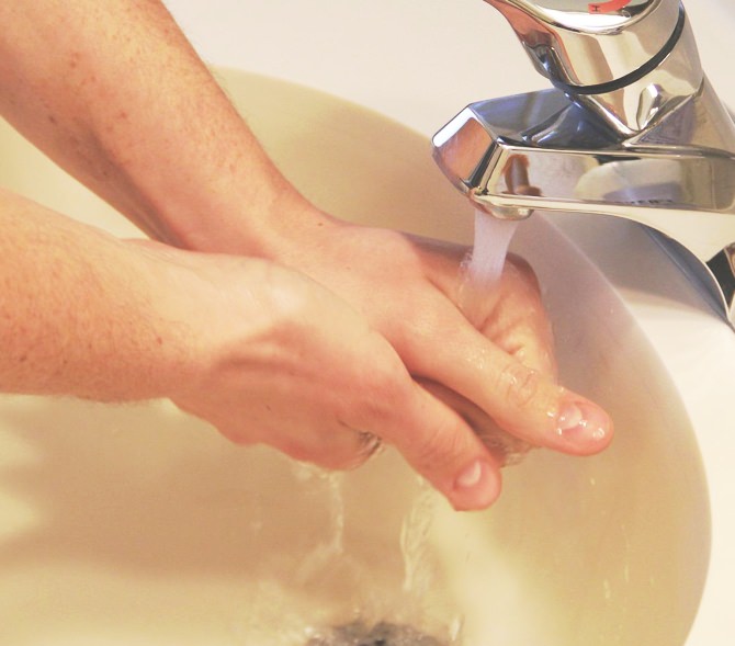 Person washing hands in public bathroom